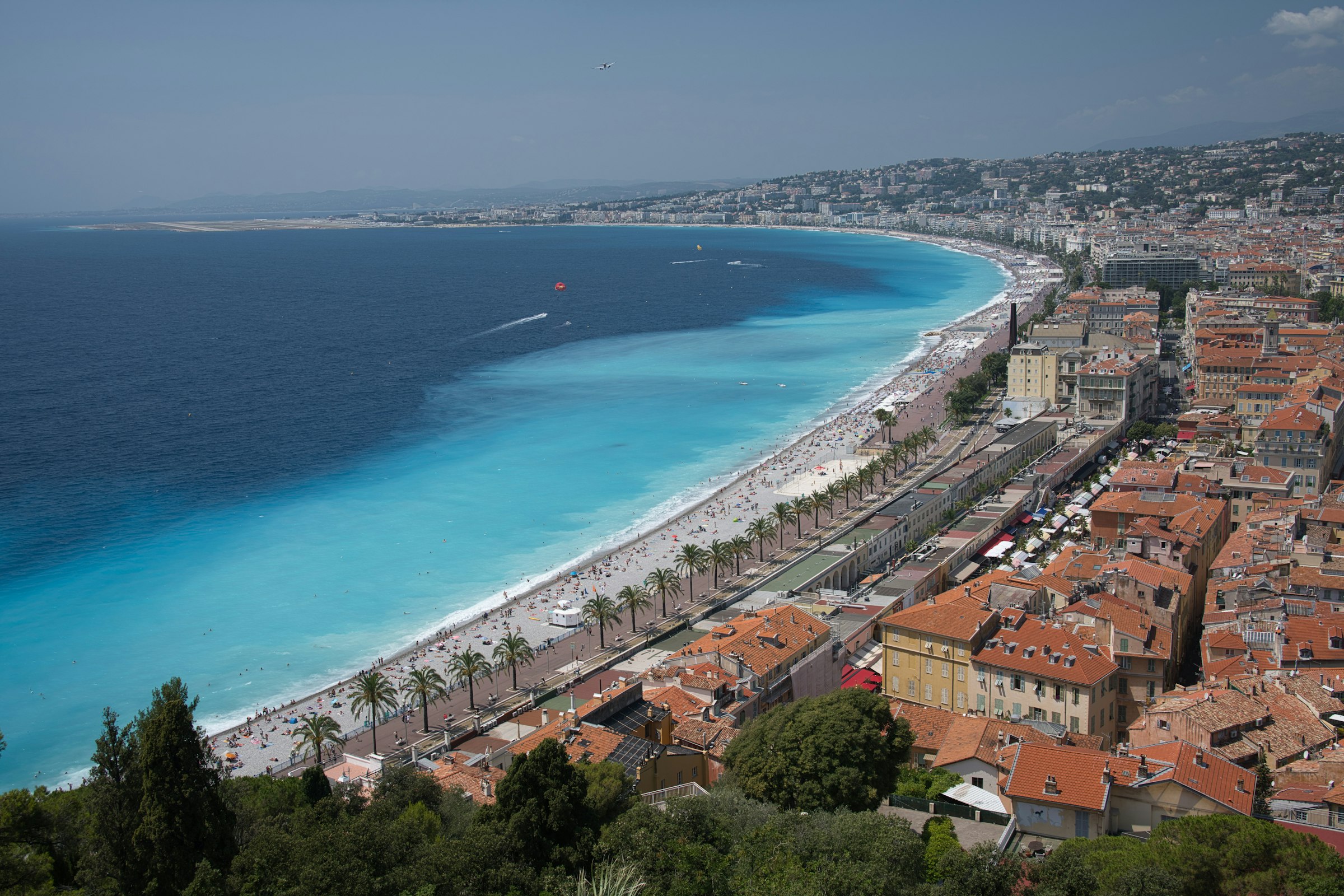 La baie des Anges à Nice vue depuis la colline du Château : mer turquoise, plage de galets et Promenade des Anglais